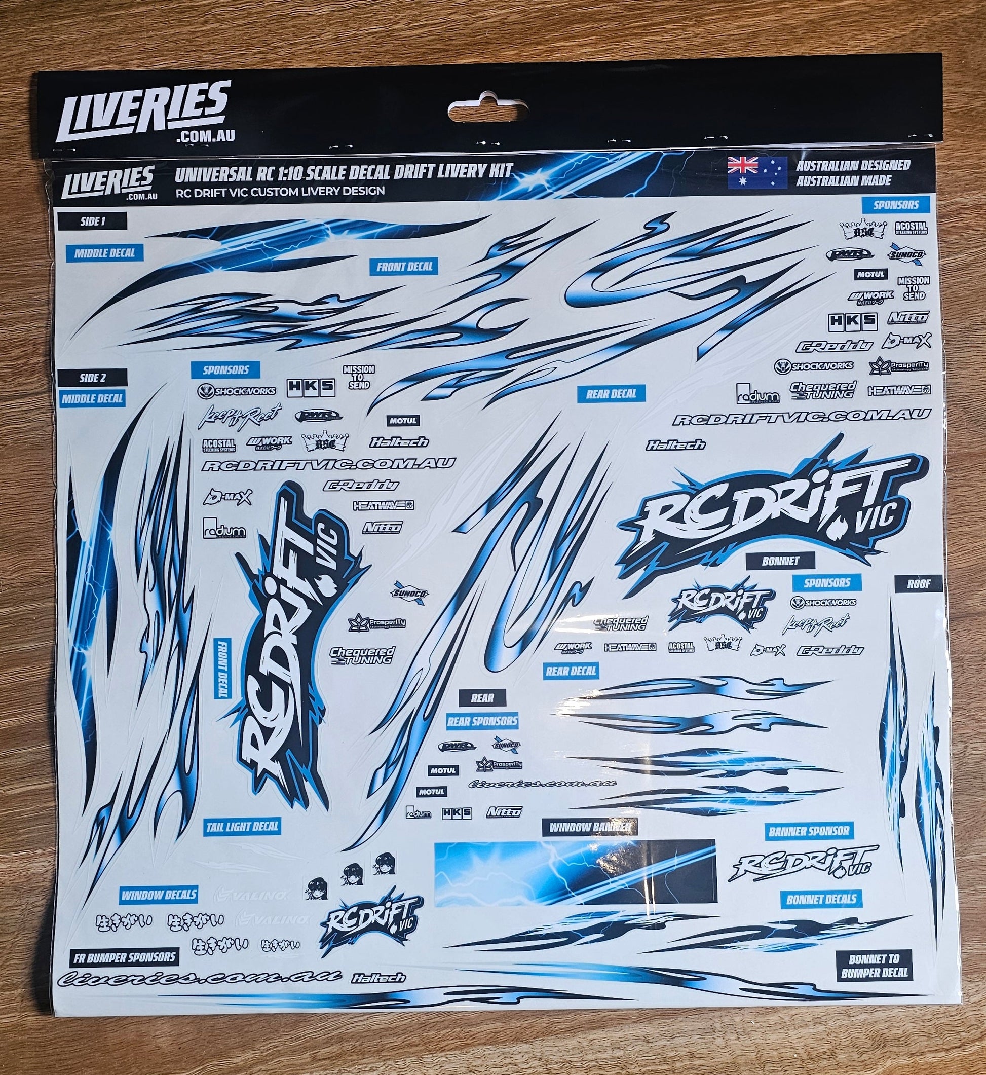 RC Drift VIC livery sticker kit – 1:10 scale RC drift decal sheet photographed on wood surface, includes blue lightning designs and RC Drift VIC sponsor logos.